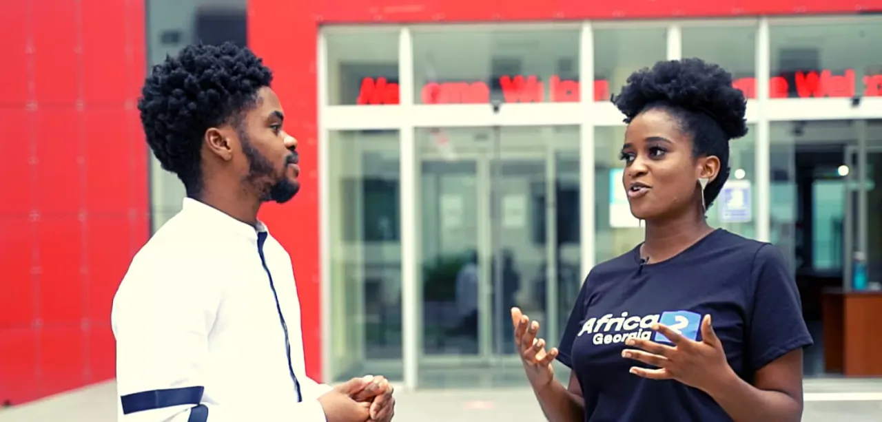 A conversation outside a university building with a woman in an Africa2Georgia T-shirt
